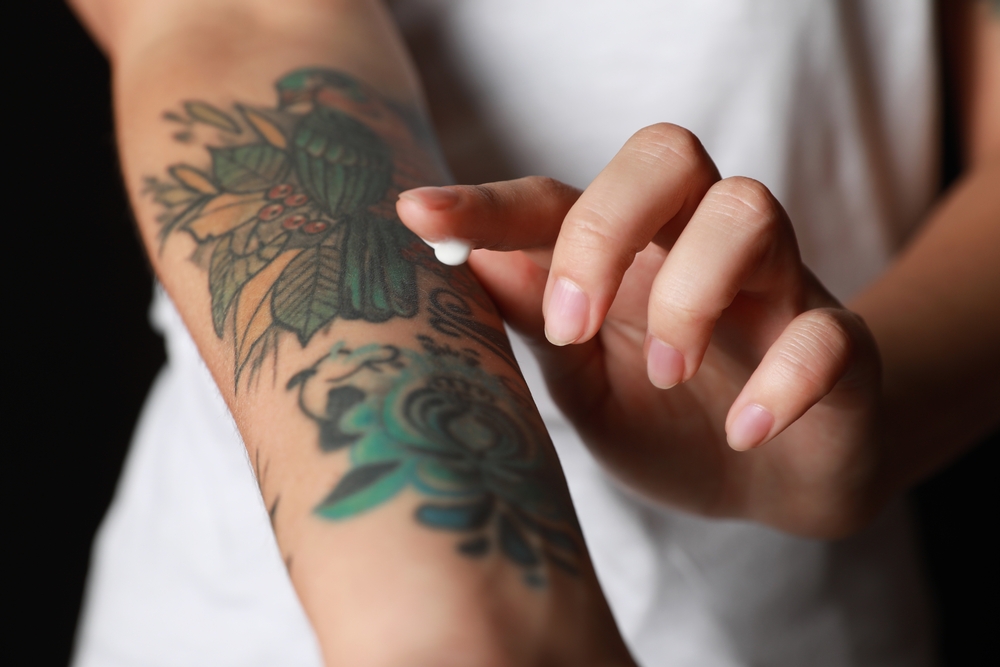 A woman applying lotion to her colour tattoo