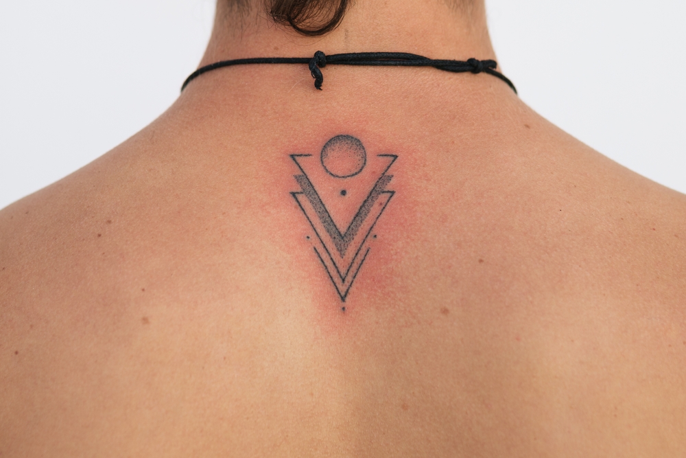 A woman shows a recent minimalist tattoo on her upper back