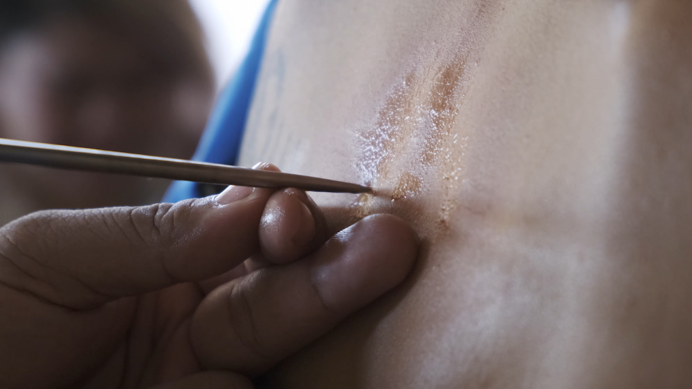 A tattoo made by using a wood tool to drive ink below the skin